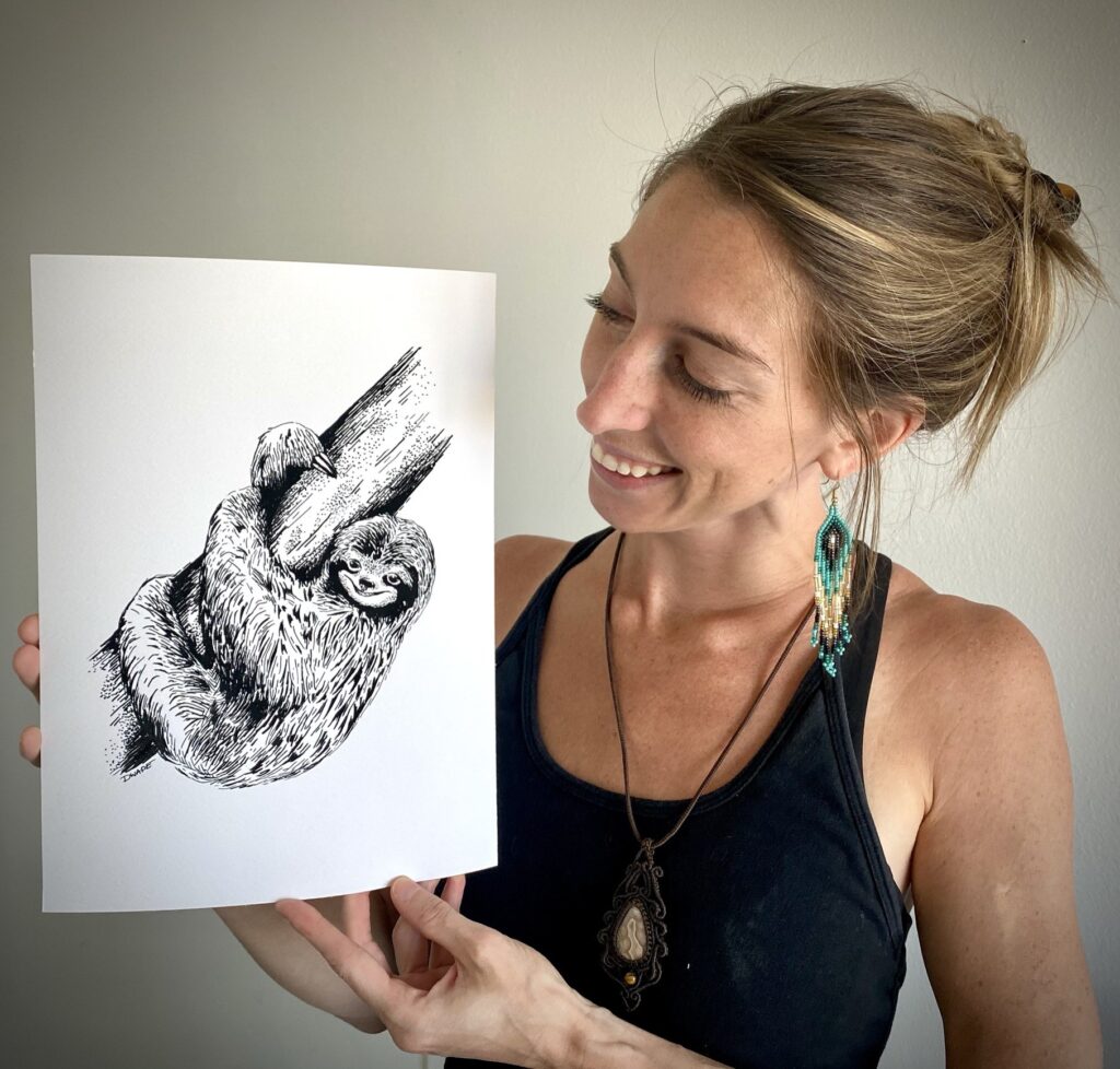 Darcy Wade holding her drawing of a sloth